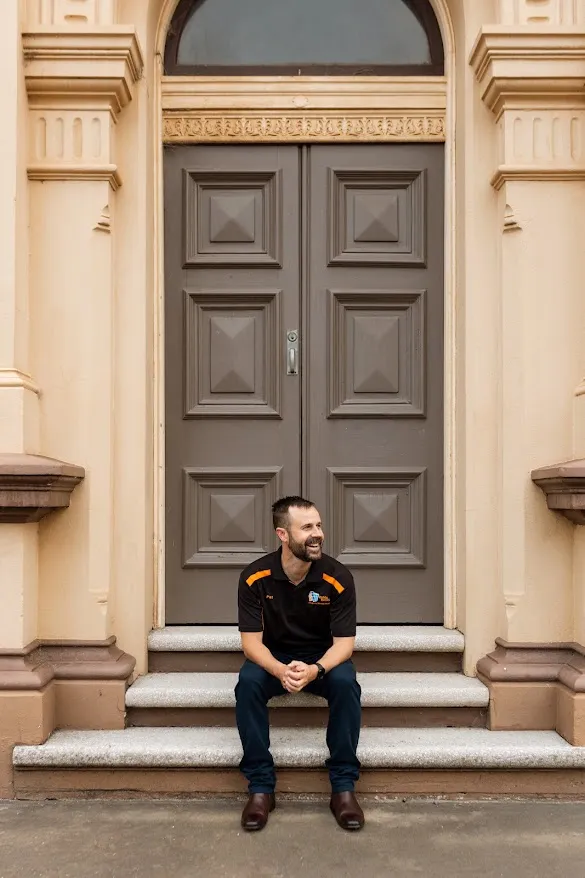 Pat Mears sitting on the front steps of a Maitland heritage building
